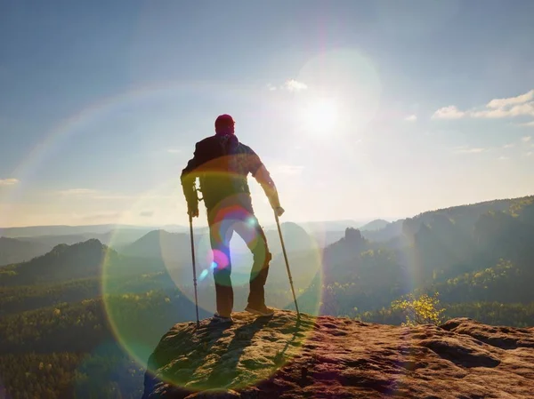 Turist izinde başının üstünde ön kol koltuk değneği ile. Uzun yürüyüşe çıkan kimse elde dağ tepe zarar