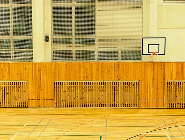 Інтер'єр шкільного спортзалу зі стінами, покритими сіткою безпеки. Великий зал з баскетбольною дошкою — стокове фото