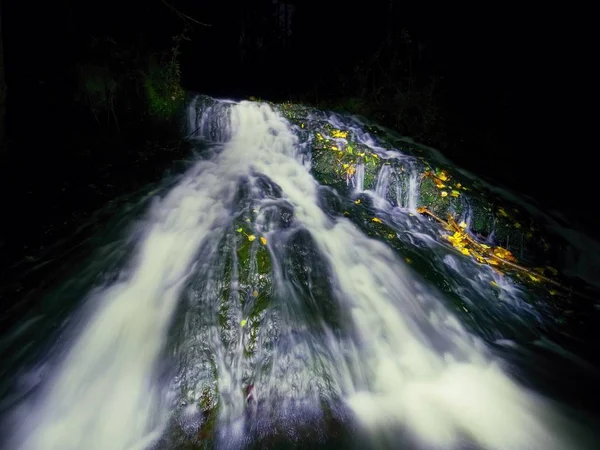 Nachtwasserfall. Wildwasserspray in Wasserfall auf Bach, schäumendes Wasser fällt über bemoosten Felsen. — Stockfoto