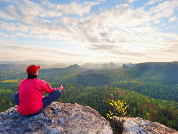 Sitzender Wanderer auf einem Felsen. Mann in roter schwarzer warmer Kleidung sitzt auf Klippe und genießt weite Sicht. — Stockfoto