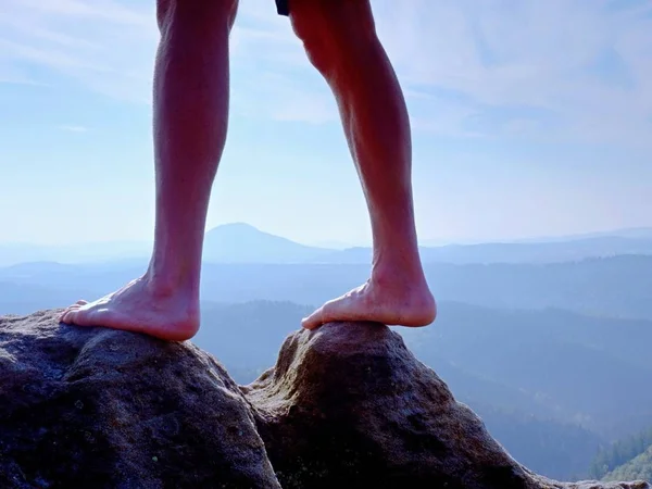 Naked male legs on peak make step. Sandstone rock above valley with tired hikers legs. — Stock Photo, Image