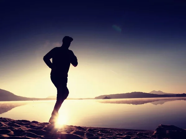 Uitoefenen op het strand bij zonsondergang, zon bij de horizon — Stockfoto