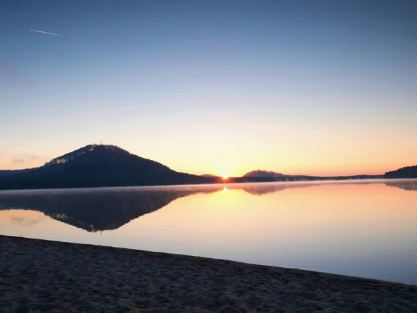 Verlassener Sandstrand am See, klarer Himmel vor Sonnenuntergang, Sonnenstrahlen am Horizont — Stockfoto