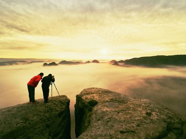 Photographying vahşi doğada. Doğa fotoğrafçısı ile büyük fotoğraf makinesi tripod üzerinde Zirvesi kayanın üzerinde kal. Muse dinlemek