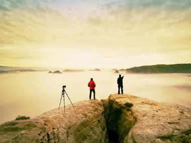 İki sıcak palto fotoğrafçılar tripod ile sonbahar manzara resimleri dağ altında ateş..