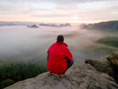 Hayattan zevk. Adam siyah pantolon, ceket ve karanlık kap içinde oturup Cliff'in kenar ve yatay olarak seyir üzerinde