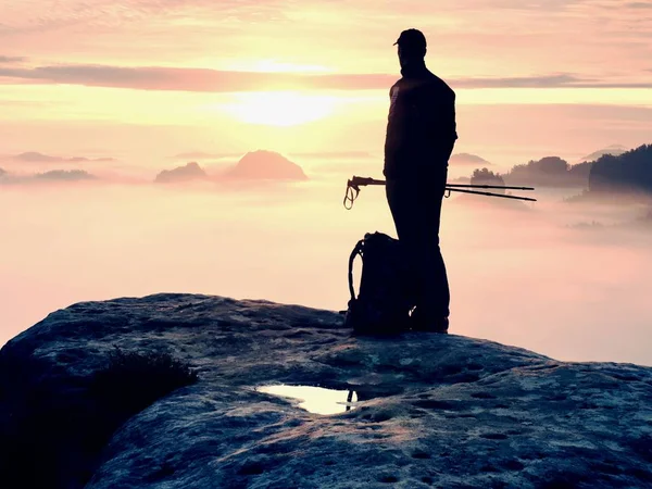 Vista posteriore al viaggiatore stand alone sulla scogliera con nebbia soffietto gambe, sole nel cielo nuvoloso — Foto Stock