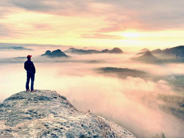 Alleen wandelaar in rode dop op piek van zandsteen rotsen in rock empires park en waakt over de mist staan — Stockfoto