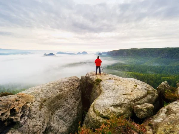 Fotograf auf dem Krater. Mann auf Gipfel über dicken Wolken, dunkles Regenwetter — Stockfoto