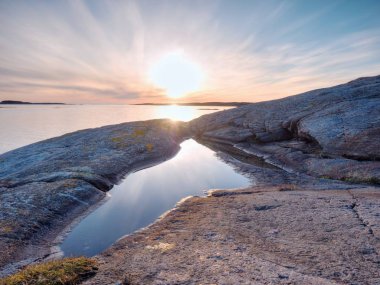 Deniz bay, kayalık sahil inanılmaz yangın sunrise. Kayalık ufuktan sıcak gün batımı