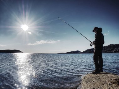 Adam iterek yem kontrol ve çok denize atar. Olta ile balıkçı