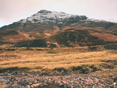 Dere dere akan su granit taşların üzerinde temizleyin. Ağır bulutları içinde karlı dağlar