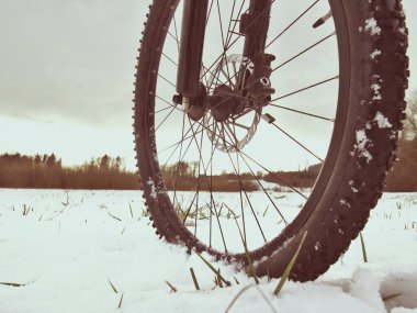 Toz karda dağ bisikleti. Rüzgârla oluşan kar yığını kayıp yolundaki. Tekerlek detay