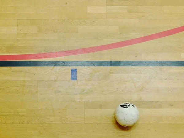Pallone da calcio e linee rosse e nere sul pavimento sportivo in legno massello. Rinnovo pavimento in legno — Foto Stock