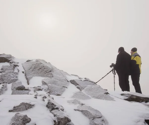 Caminante y entusiasta de la fotografía se quedan en el pico nevado en el trípode. Hombres en el acantilado hablando y pensando . — Foto de Stock