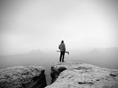 Uzun yürüyüşe çıkan kimse ile fotoğraf makinesi tripod üzerinde kayalık Zirvesi resimden alır. Yalnız fotoğrafçı Zirvesi
