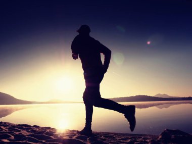 Atletik runner gündoğumu karşı sahilde koşu silüeti.