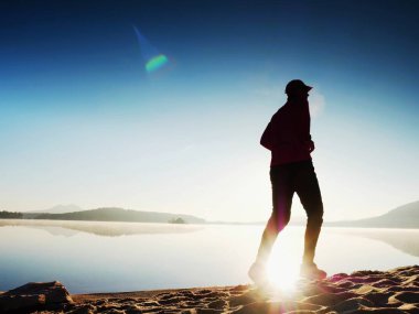 Atletik runner gündoğumu karşı sahilde koşu silüeti.