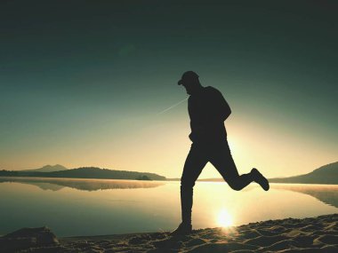 Atletik runner gündoğumu karşı sahilde koşu silüeti.