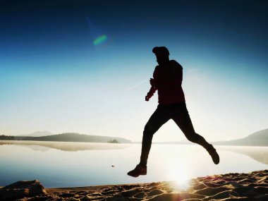 Atletik runner gündoğumu karşı sahilde koşu silüeti.