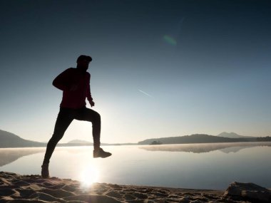 Atletik runner gündoğumu karşı sahilde koşu silüeti.