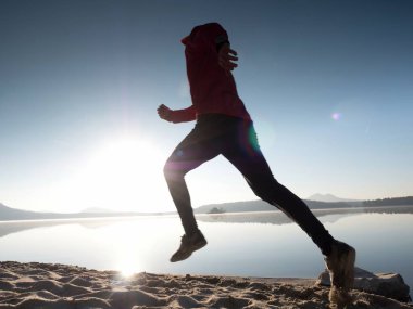 Atletik runner gündoğumu karşı sahilde koşu silüeti.