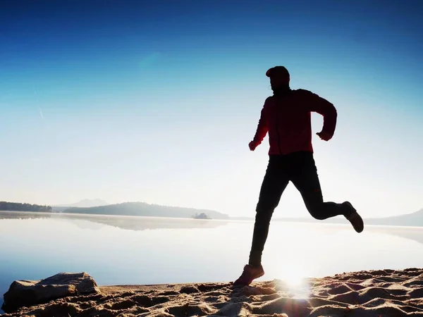 Silueta de corredor atlético corriendo en la playa contra el amanecer . — Foto de Stock