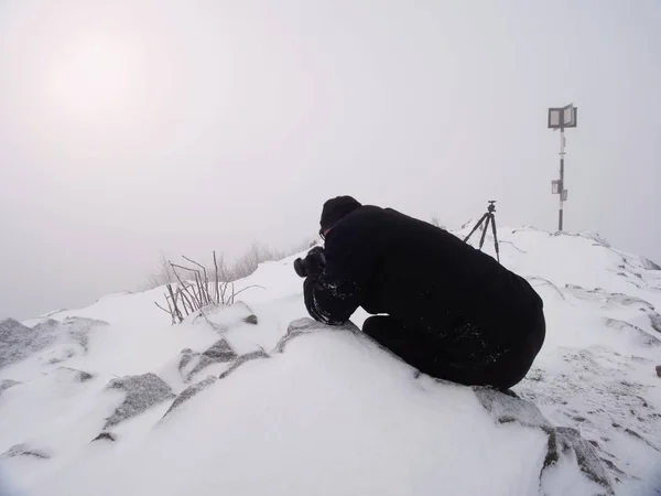 Fotógrafo profesional se acuesta a la nieve y toma fotos con cámara de espejo en el pico —  Fotos de Stock
