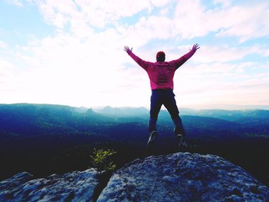 Adam atlama. Genç deli adam manzara üzerinde kayalık zirvesinde atlıyor. Adam atlama siluet