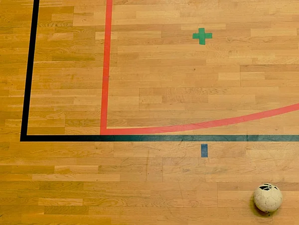Μπάλα ποδοσφαίρου σάλας και κόκκινες και μαύρες γραμμές στο σκληρό ξύλο αθλητικών δαπέδων. Ανανέωση ξύλινο πάτωμα — Φωτογραφία Αρχείου