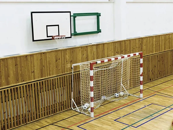 Interior do ginásio da escola com paredes cobertas por rede de segurança. Grande salão com placa de basquete — Fotografia de Stock
