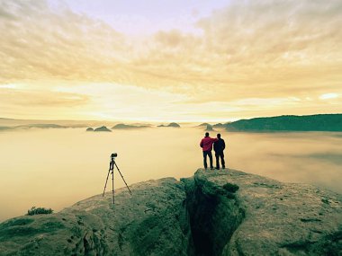 İki sıcak palto fotoğrafçılar tripod ile sonbahar manzara resimleri dağ altında ateş..