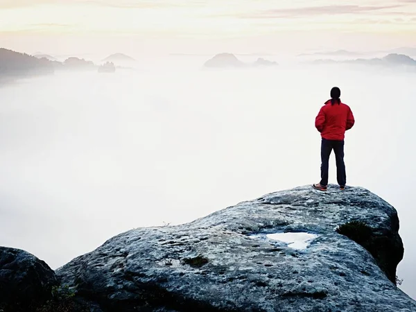 Οπίσθια όψη να ταξιδιώτη αυτοδύναμη στον γκρεμό με πόδια παρακάτω ομίχλη, ηλιοφάνεια σε συννεφιά — Φωτογραφία Αρχείου