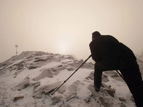 Professional photographer lay down to snow and takes photos with mirror camera on peak