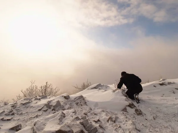 Фотограф лежит в снегу на вершине горы и фотографирует фантастический пейзаж — стоковое фото