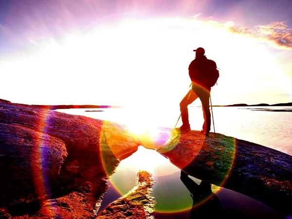 Man, sea and sun at horizon. Traveler on rocky cliff above sea enjoy view.