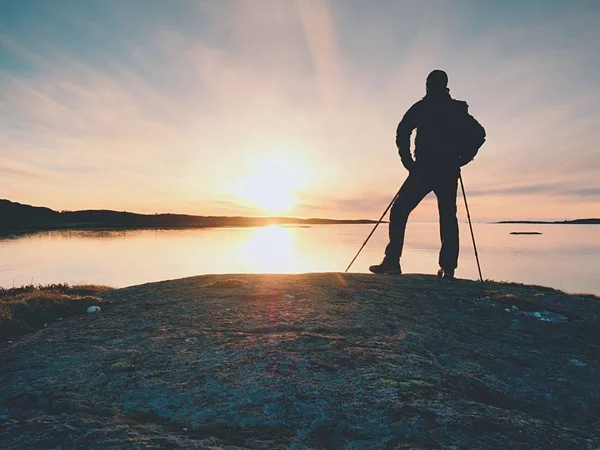 Voyageur avec sac à dos debout sur la rive rocheuse et regardant le lever du soleil. Falaise rocheuse — Photo