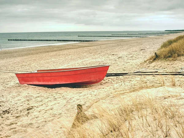 Abandoned red paddle boat on sandy beach of sea.  Smooth water level — Stock Photo, Image