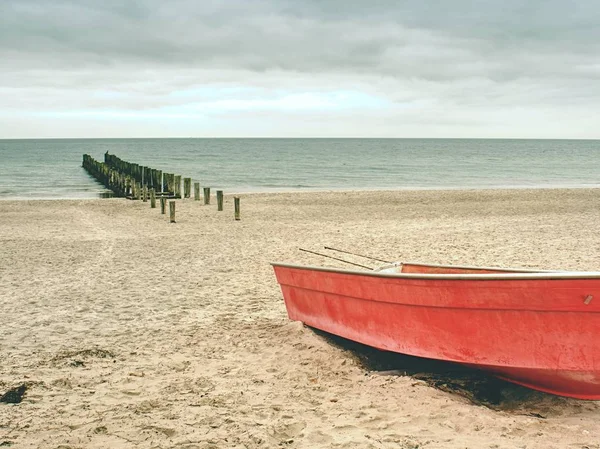 Kırmızı kürek tekne deniz kumlu plaj üzerinde terk edilmiş. Yumuşak su seviyesi — Stok fotoğraf