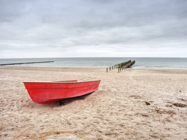 海の砂浜のビーチで赤パドル船を放棄しました。滑らかな水位 — ストック写真