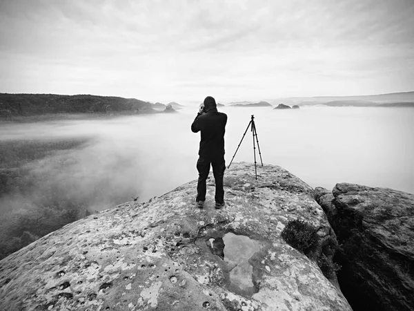 Fotograf på kratern. Man på topp över tjockt moln, mörkt regnigt väder — Stockfoto