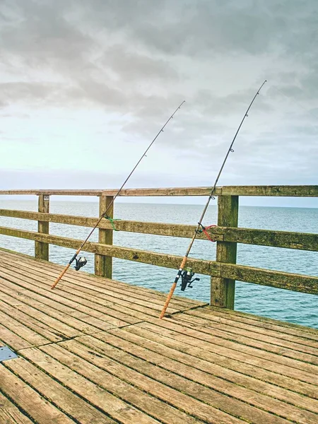 Ψάρεμα στη θάλασσα γέφυρα. Ράβδοι αλιείς κατά την ξύλινη κουπαστή από το μόλο της παραλίας. — Φωτογραφία Αρχείου