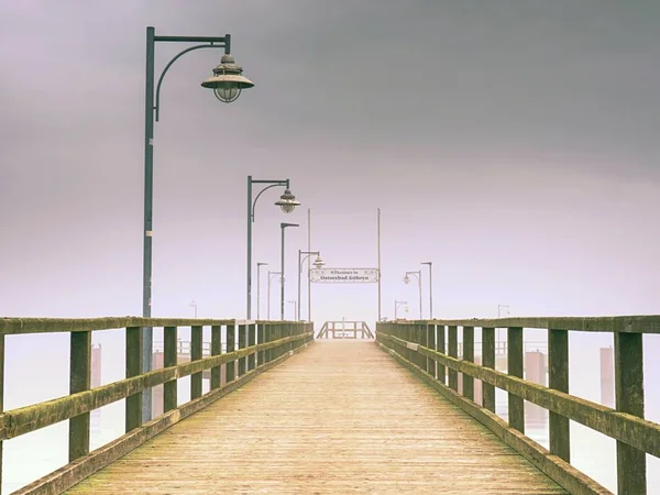 Molo di legno vuoto nel porto. Portalampada in acciaio, orizzonte nascosto nella fitta nebbia. Nebbia autunnale — Foto Stock