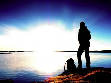 Yalnız adam doğru canlı günbatımı bakan silüeti. İşaret fişeği ve içinde yansıyan sığ sularda