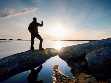 Deniz akşam gökyüzü karşı doğal görünümü karşı cep telefonunda selfie alarak yüksek turist. Güneş ayna