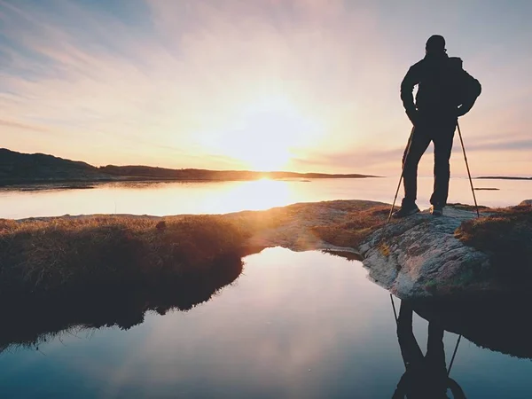 Giovane in piedi con lo zaino. Escursionista sulla pietra sulla riva del mare al colorato cielo del tramonto . — Foto Stock