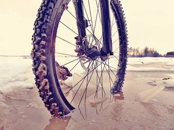 车轮掉进泥泞的水坑, 而冬季山地车旅行。雪下隐藏的水. — 图库照片