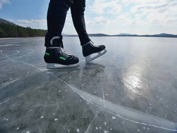 Man schaatsen op de bevroren meer. Dun ijs met deeep scheuren onder man — Stockfoto