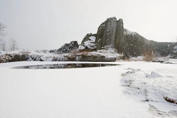 화산 바위 언덕 흐린 겨울 일몰 동안 눈으로 덮여. — 스톡 사진