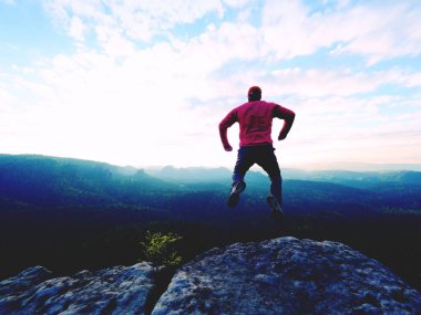 Adam tehlikeli kenarına atlama. Adam atlamak. Genç adam renkli gökyüzü arka plan üzerinde düşme.